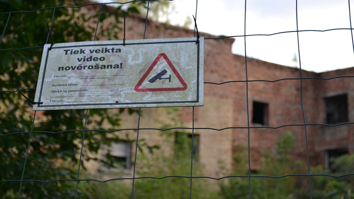 a sign is posted on a fence near a building