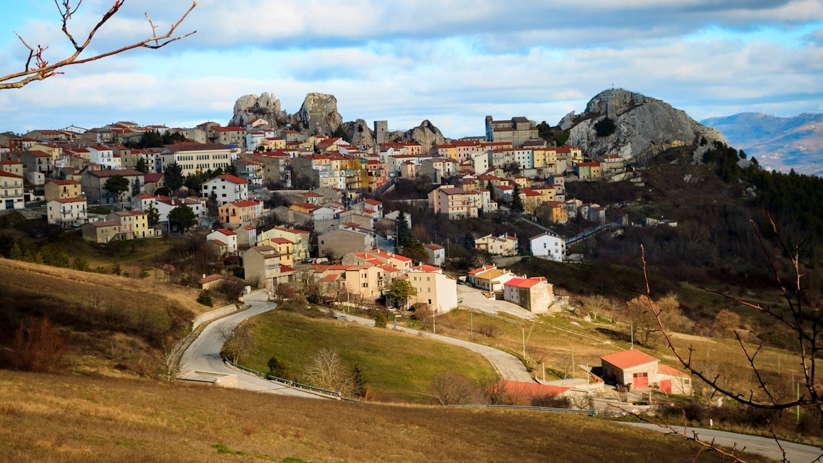 brown and white concrete houses on green grass field under white clouds during daytime